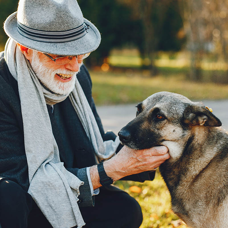 Man in hat caresses dog.